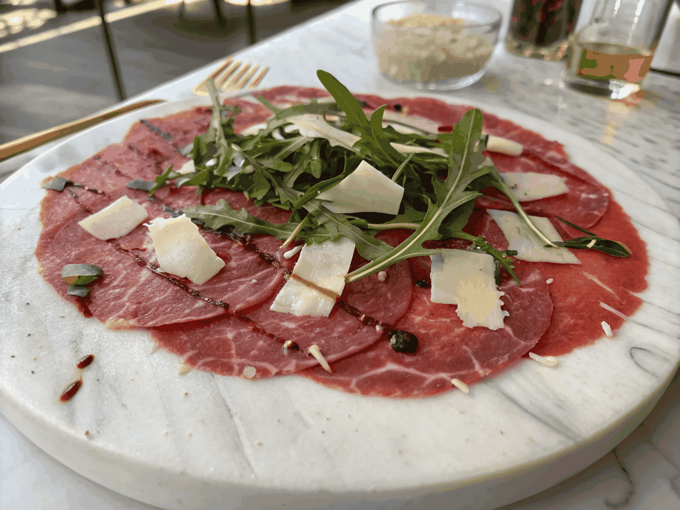 Thinly sliced beef carpaccio topped with black truffles and microgreens
