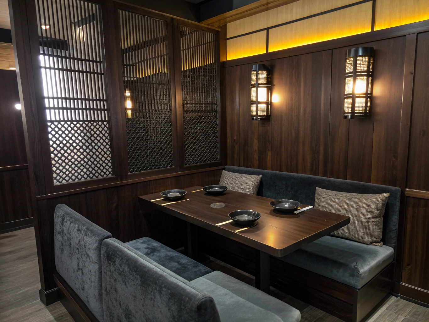Cozy velvet upholstered dining booth lit by warm sconces